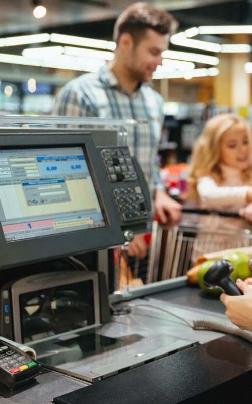 Beautiful family standing at the cash counter buying groceries at the supermarket